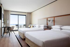 a hotel room with three beds and a table with a desk at Riviera Marriott Hotel La Porte De Monaco in Cap d'Ail
