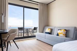 a living room with a couch and a table with chairs at Riviera Marriott Hotel La Porte De Monaco in Cap d'Ail