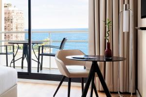 a room with a table and a chair and a balcony at Riviera Marriott Hotel La Porte De Monaco in Cap d'Ail
