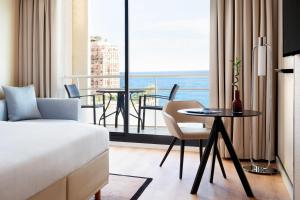 a hotel room with a bed and a table and chairs at Riviera Marriott Hotel La Porte De Monaco in Cap d'Ail