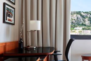 a table and a lamp in a room with a window at Riviera Marriott Hotel La Porte De Monaco in Cap d'Ail