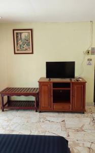 ein Entertainment-Center mit einem Flachbild-TV und einer Bank in der Unterkunft Tientong Guesthouse in Hua Hin