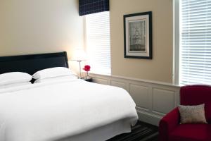 a bedroom with a white bed and a red chair at Sheraton Columbia Downtown Hotel in Columbia