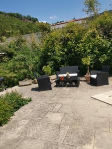 un patio con 2 sillas, un sofá y una mesa en Le P'tit gîte en Saint-Privat