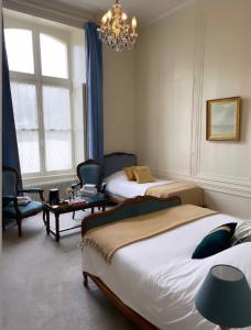 ein Schlafzimmer mit zwei Betten und einem Kronleuchter in der Unterkunft Hôtel du Château de Quinéville in Quinéville