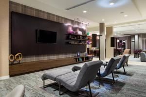 een lobby met stoelen en een tv aan de muur bij Courtyard by Marriott Elmira Horseheads in Horseheads