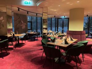 a restaurant with tables and chairs and windows at Hotel Allmer in Bad Gleichenberg