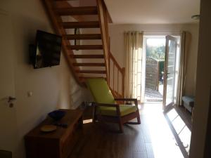 una sala de estar con una silla verde y una escalera en Aloha 1, en Neue Tiefe Fehmarn