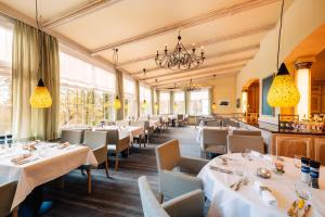 a restaurant with white tables and chairs and windows at MUNTE - Wellnesshotel am Stadtwald in Bremen