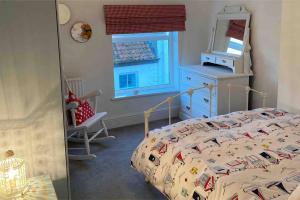 1 dormitorio con cama, ventana y espejo en Lilly’s Cottage, Filey, Sleeps 8 en Filey