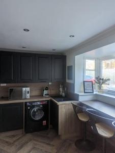 a kitchen with black cabinets and a washer and dryer at Cottage/boutique style - Free parking & Wi-Fi in Hull