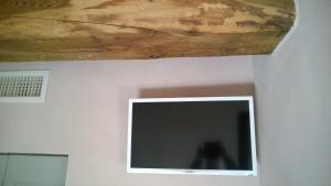 una TV a schermo piatto a parete con soffitto in legno di Il vicoletto di BIBI - B&B a Staffolo