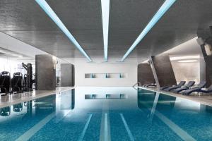 - une piscine avec des chaises dans un bâtiment dans l'établissement JW Marriott Hotel Beijing, à Pékin