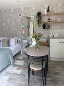 a room with a table and a bed and a kitchen at The Garden room in Honiton
