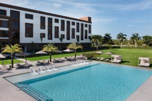 uma imagem de um hotel com piscina e cadeiras em AC Hotel by Marriott Punta Cana em Punta Cana