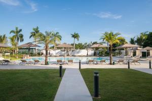 - une piscine avec des chaises et des parasols dans un complexe dans l'établissement AC Hotel by Marriott Punta Cana, à Punta Cana