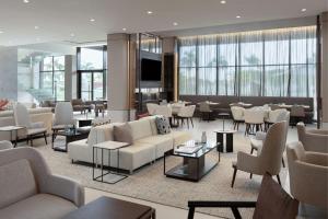 un vestíbulo de hotel con sofás, mesas y sillas en AC Hotel by Marriott Punta Cana en Punta Cana