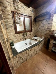 La salle de bains est pourvue d'une baignoire dans un mur en pierre. dans l'établissement Casita rural con piscina, à La Torre de Claramunt