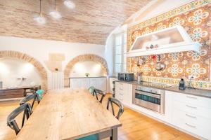 eine große Küche mit einem Holztisch und Stühlen in der Unterkunft Archi di Castello, Storia e Design 3Br-WiFi-AC in Cagliari