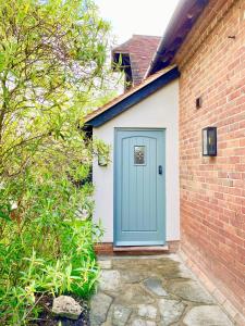 a blue door on the side of a brick building at Beautiful 3 bed cottage in Lymington. Perfectly located for Coast and New Forest in Lymington
