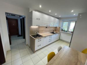 科馬爾諾的住宿－Apartman Bibi-D，厨房配有白色橱柜和一张带黄色椅子的桌子