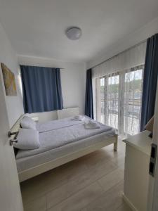 1 dormitorio con 1 cama con cortinas azules y ventana en Apartamente9- Serena de închiriat, en Băile Felix