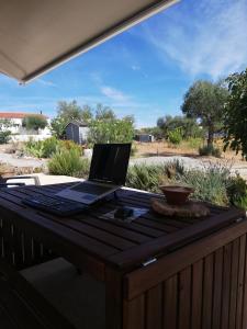 un ordenador portátil sentado en una mesa en una cubierta en Burrico D`Orada - Lodging & Experiences en Pedrógão