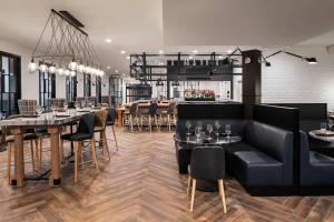 un ristorante con divani neri, tavoli e sedie di Delta Hotels by Marriott Green Bay a Green Bay