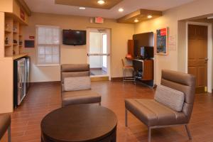 マイアミ・レイクスにあるTownePlace Suites Miami Lakesの椅子、テーブル、テレビ付きの待合室