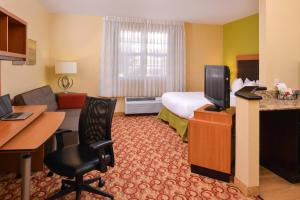 a hotel room with a bed and a desk and a television at TownePlace Suites Miami Lakes in Miami Lakes