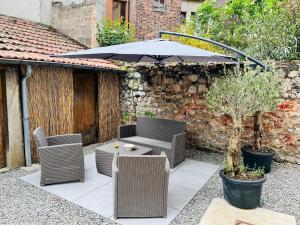 une terrasse avec une table, des chaises et un parasol dans l'établissement La Jungle d'Orient - Confort - Garage à vélos, à Montluçon
