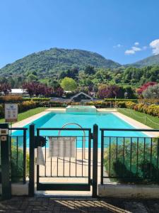 a swimming pool behind a gate with a mountain in the background at giardino e piscina apartment in Bellagio