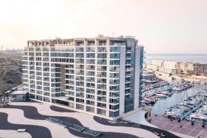 - un grand bâtiment à côté d'un port de plaisance avec des bateaux dans l'établissement The Ritz-Carlton, Herzliya, à Herzliya