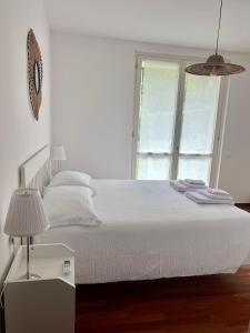 een slaapkamer met een wit bed en een raam bij giardino e piscina apartment in Bellagio