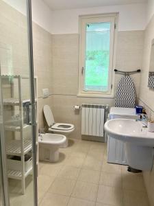 een badkamer met een wastafel en een toilet en een raam bij giardino e piscina apartment in Bellagio