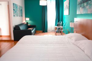 a bedroom with a large white bed and a couch at Principe Alogna Hotel & SPA in Altavilla Milicia