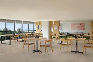 a restaurant with tables and chairs and windows at Four Points by Sheraton Balikpapan in Balikpapan