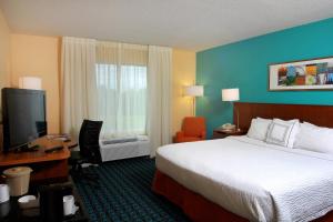 Fairfield Inn & Suites Traverse City في ترافيرس سيتي: غرفة فندقية فيها سرير ومكتب وتلفزيون