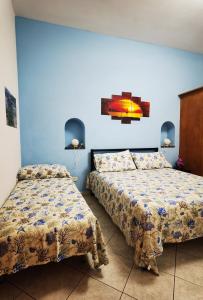 two beds in a room with blue walls at Appartamento Central in Lipari