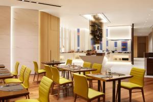 a restaurant with wooden tables and yellow chairs at Aloft Seoul Myeongdong in Seoul