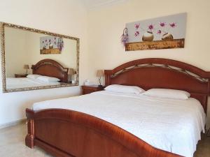 - une chambre avec un grand lit en bois et un miroir dans l'établissement Villa Tres Palmeras en Alfaz del Pi , Albir, Benidorm, à L'Alfàs del Pi