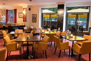 un restaurante con mesas, sillas y ventanas en Courtyard by Marriott Düsseldorf Seestern en Düsseldorf