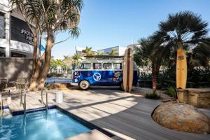 une camionnette bleue garée à côté d'une piscine avec une planche de surf dans l'établissement Protea Hotel Fire & Ice! by Marriott Durban Umhlanga Ridge, à Durban