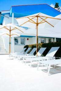 a row of white chairs and umbrellas in front of a building at Principe Alogna Hotel & SPA in Altavilla Milicia