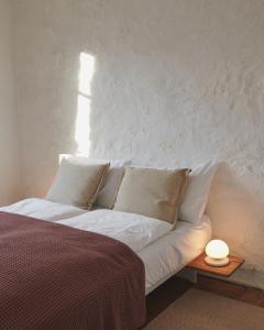 a bed with white pillows and a lamp on a table at Auberge du Mouton in Porrentruy
