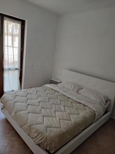 a large bed in a white bedroom with a window at Yellow house 2 in Cuasso Al Monte