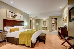 a hotel room with a large bed and a bathroom at Protea Hotel by Marriott Transit O.R. Tambo Airport in Kempton Park