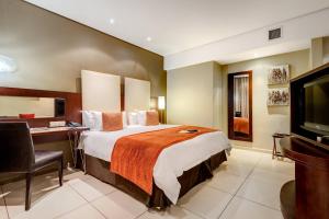 a hotel room with a bed and a desk and a television at Protea Hotel by Marriott Transit O.R. Tambo Airport in Kempton Park