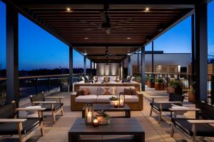 a patio with a couch and tables on a balcony at The Ellison, Oklahoma City, a Tribute Portfolio Hotel in Oklahoma City