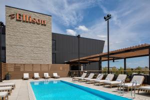 une piscine avec des chaises longues et un hôtel dans l'établissement The Ellison, Oklahoma City, a Tribute Portfolio Hotel, à Oklahoma City